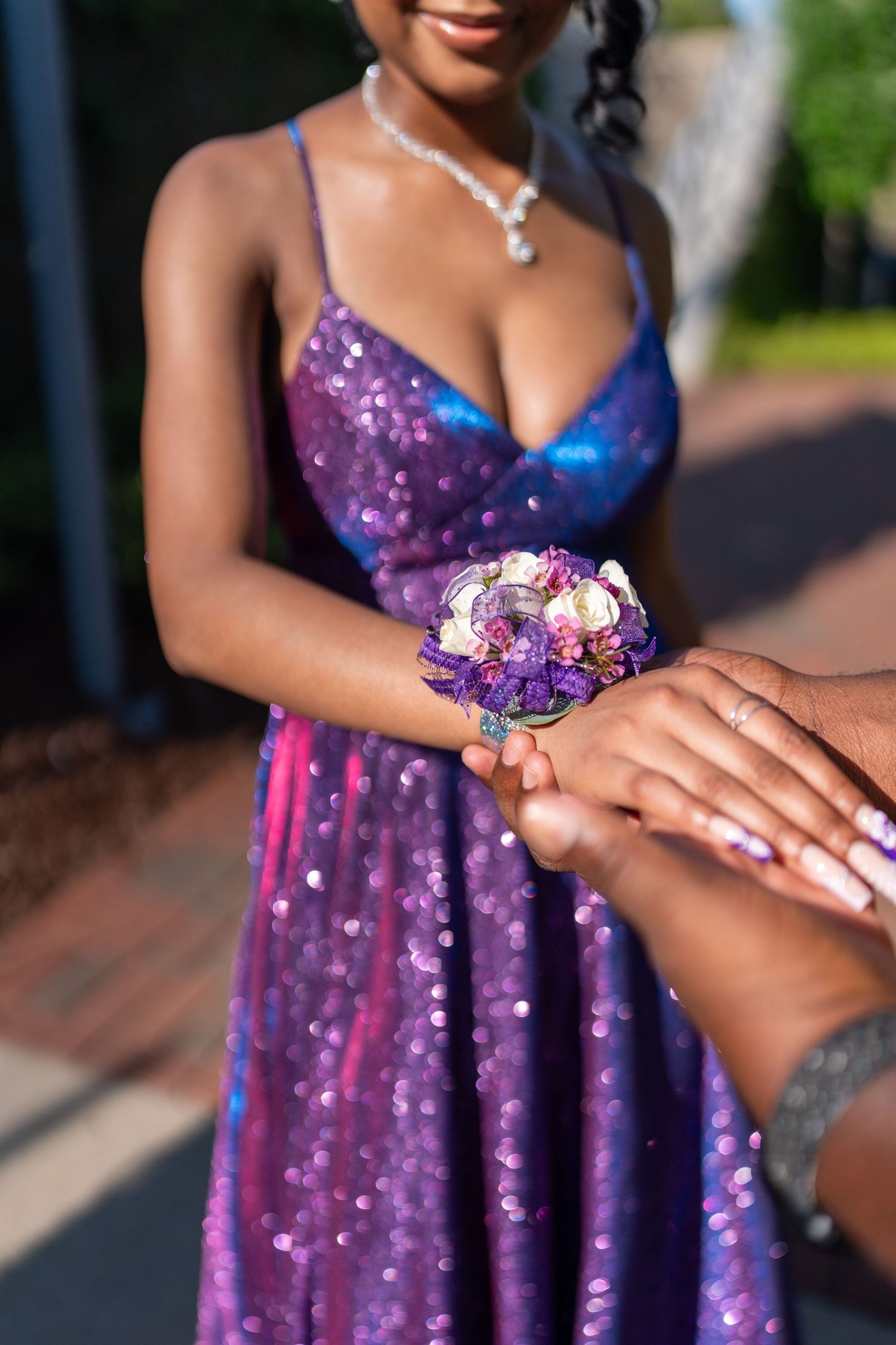 Close up of sparkly purple dress and corsage with matching jewelry.