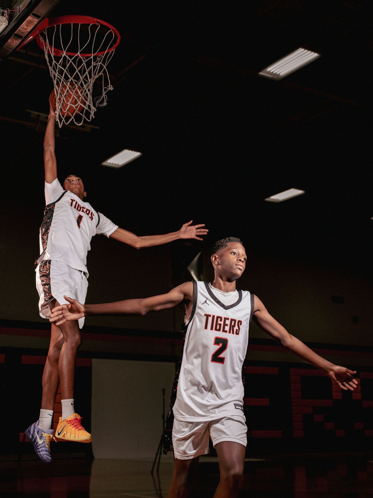 Basketball players leap high during an intense game sequence showing multiple dynamic jumping and dunking actions.