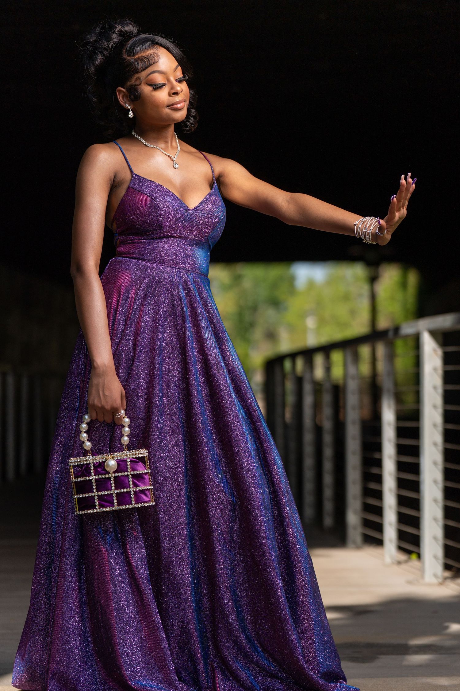 Dramatic pose in sparkly purple formal dress with small matching handbag.