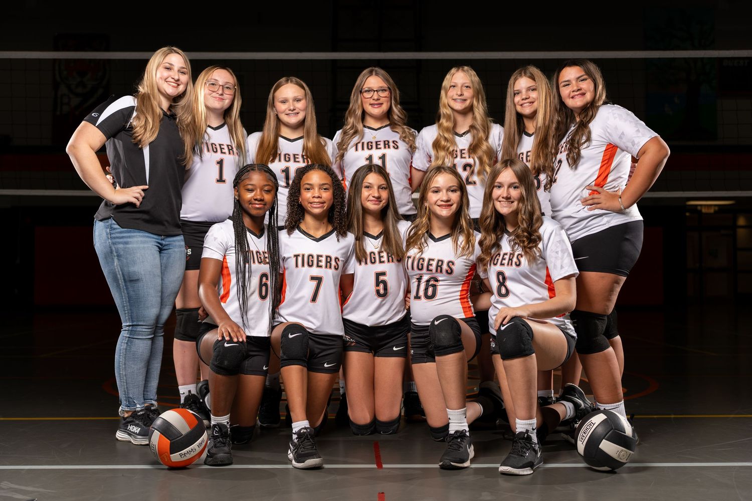 Group of volleyball players in brown and white uniforms pose together for team photo session.