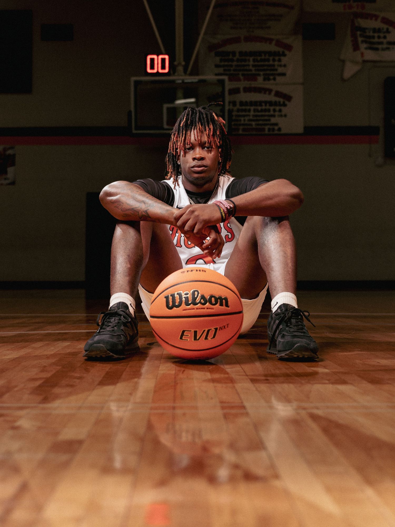 Close up view of basketball player's legs and Wilson basketball on hardwood court floor.