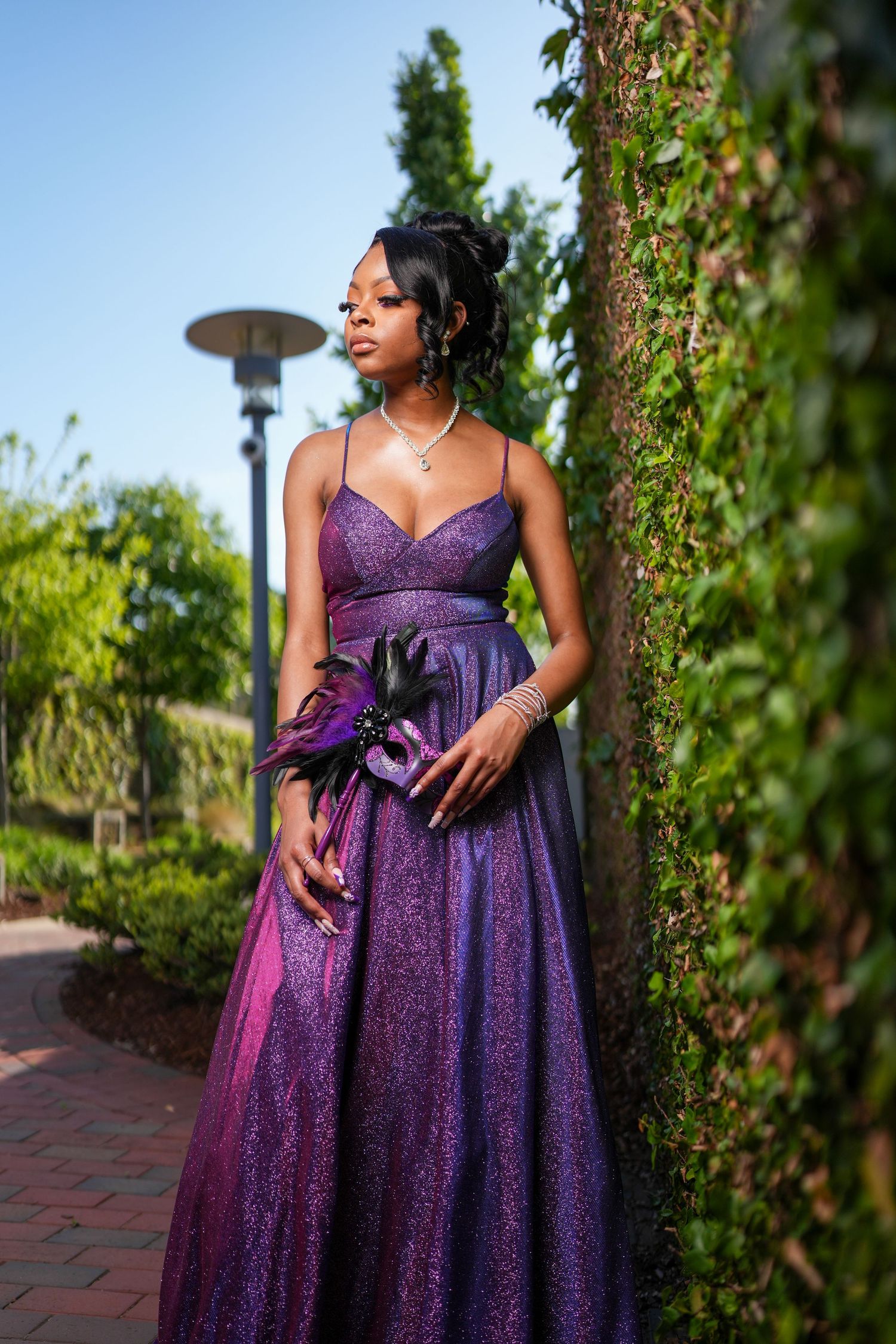 Purple ballgown photographed against ivy covered wall and garden setting.