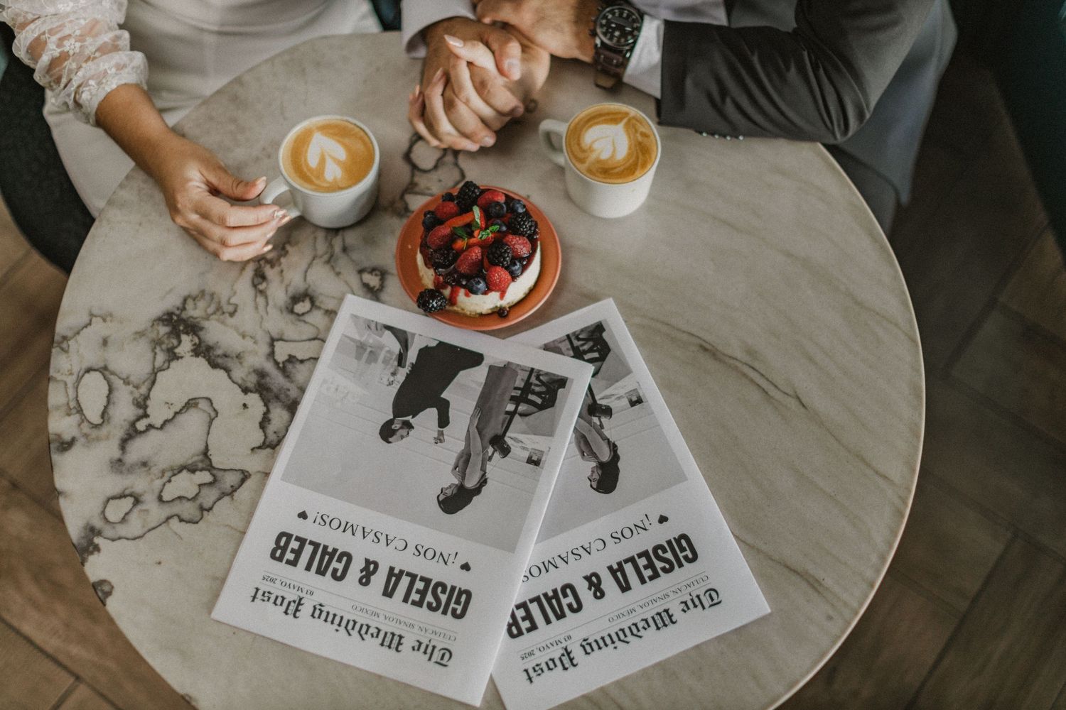 Coffee cups and a dessert on marble table with printed media materials.