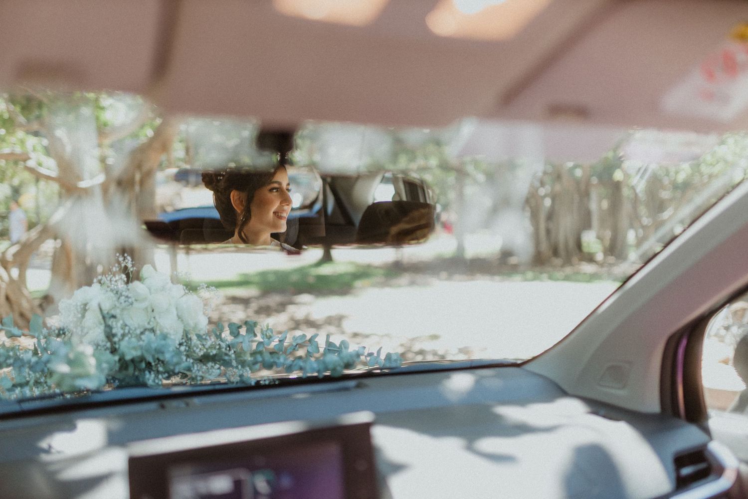 View through car windshield on a sunny day with rearview mirror visible.