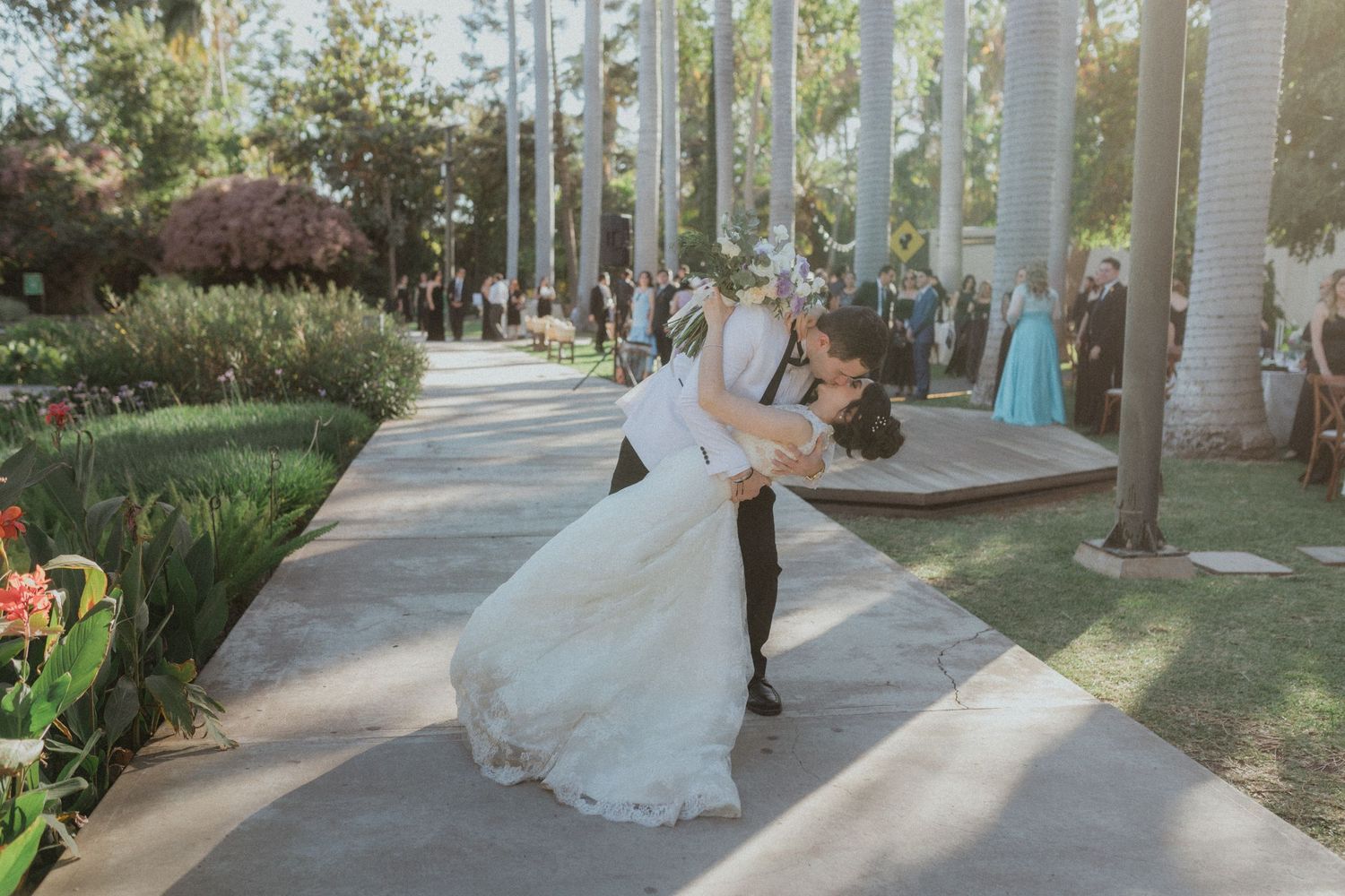 Romantic moment captured on a garden pathway surrounded by palm trees.