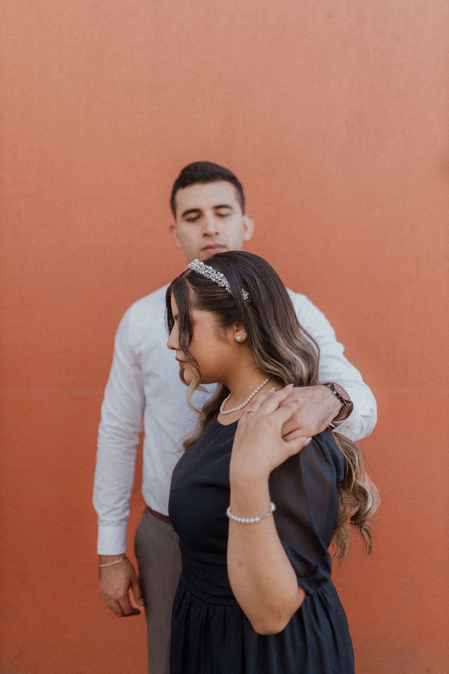 A romantic portrait against a terracotta wall showcasing intimate body language.