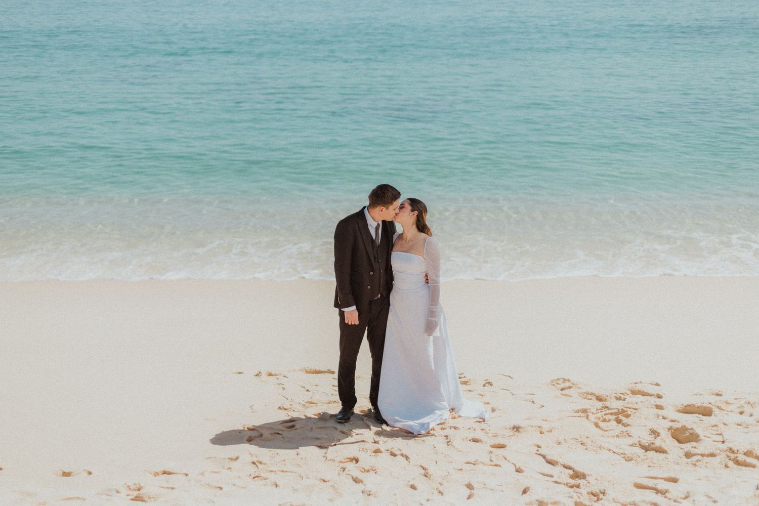 A romantic beach wedding photoshoot with turquoise ocean waters in the background.