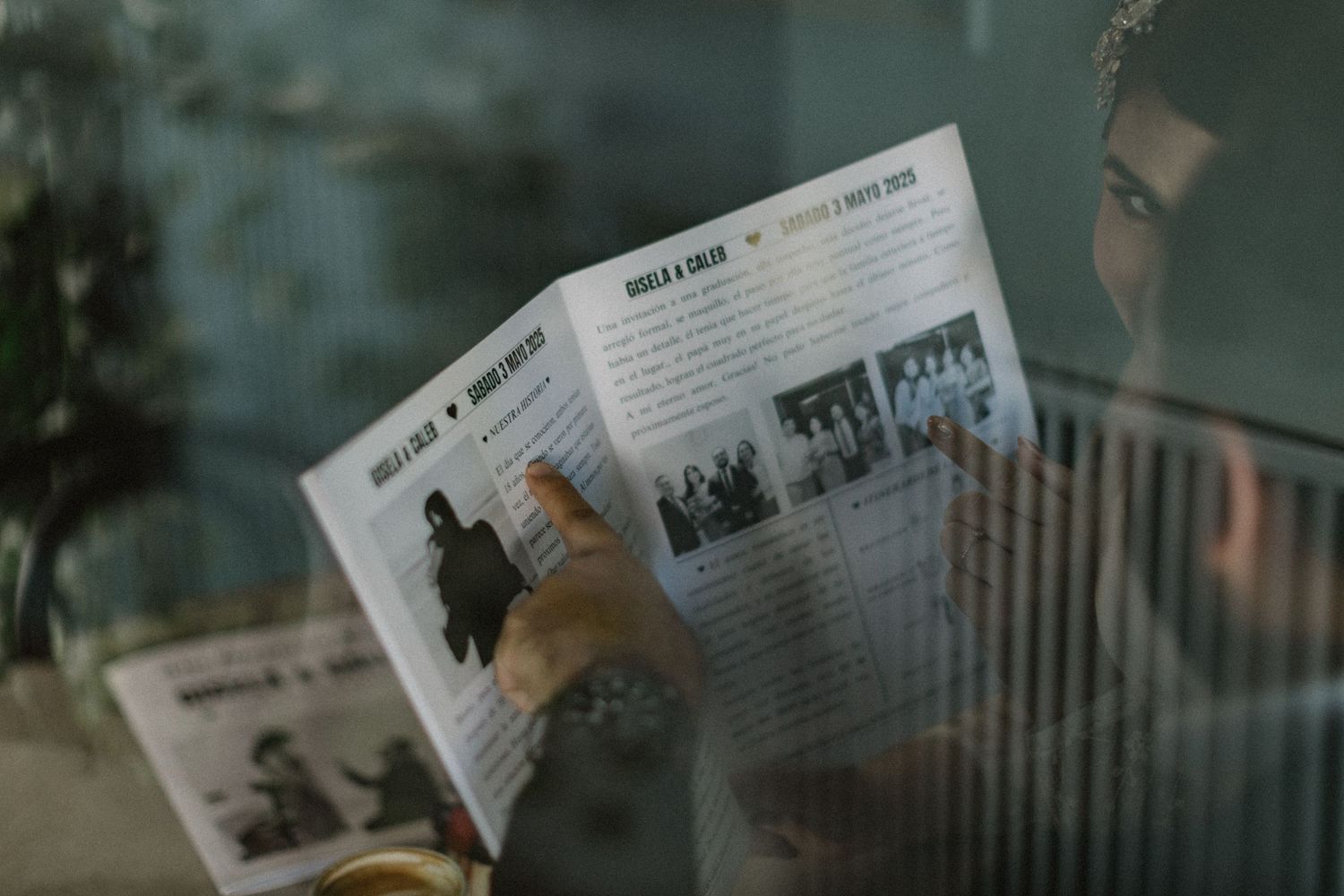 Someone reads through a magazine or brochure on a cafe table.