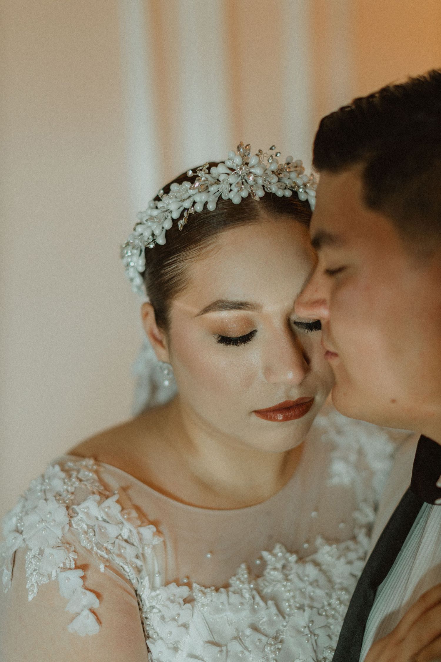 Romantic close-up of newlyweds with intricate lace dress details and floral crown.