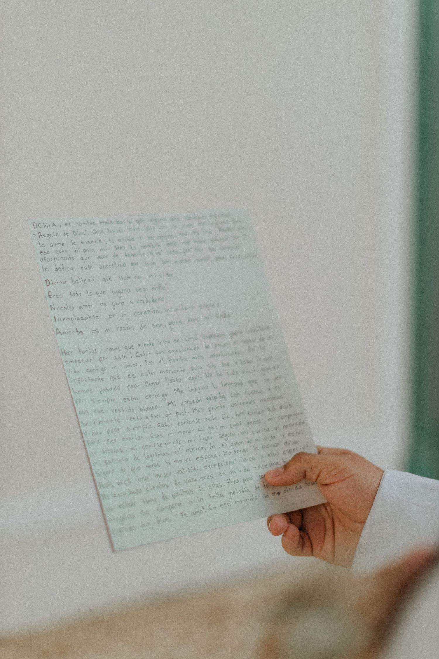 Hand holding a handwritten letter on mint green paper.
