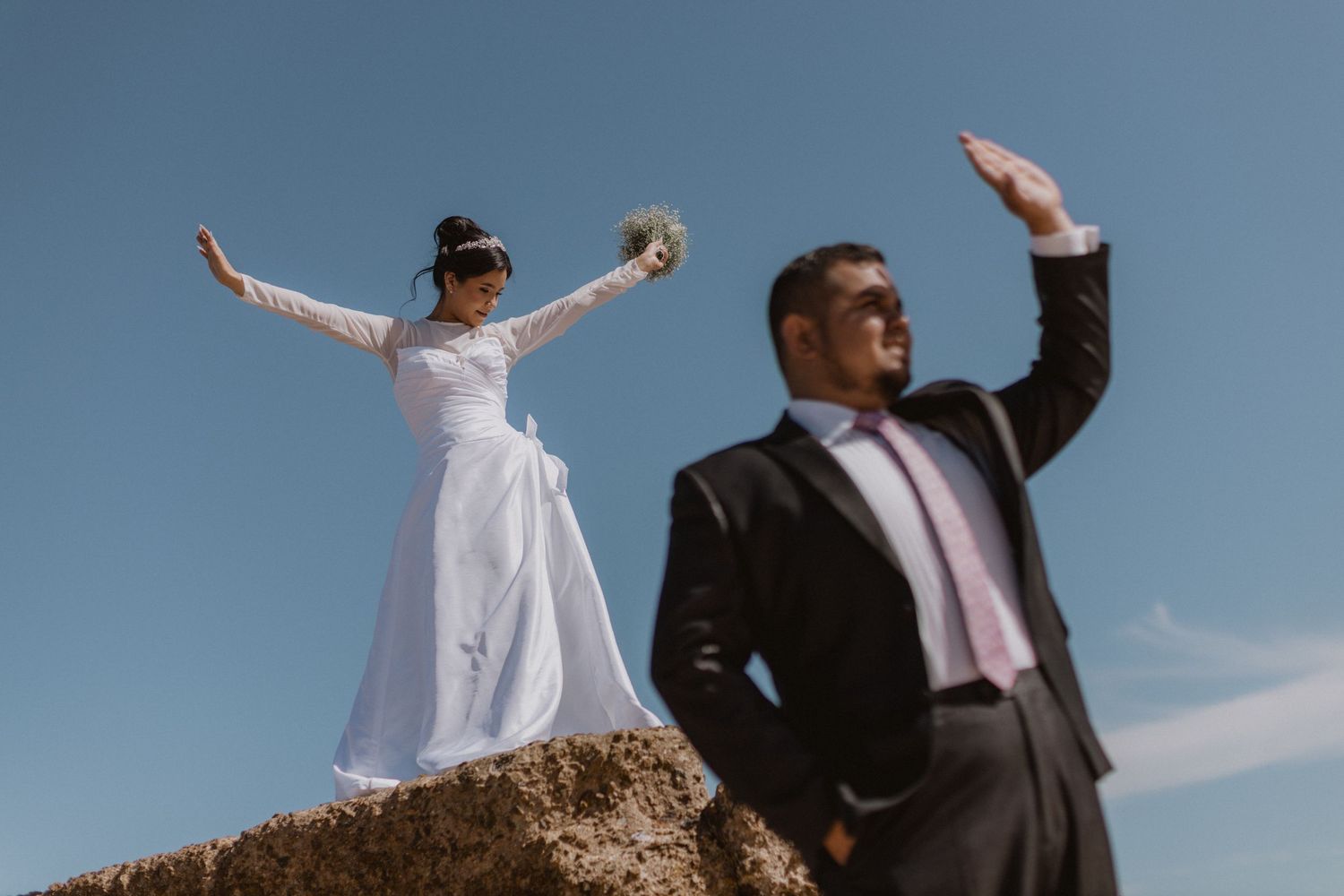 Wedding couple silhouetted against blue sky during outdoor photo session.