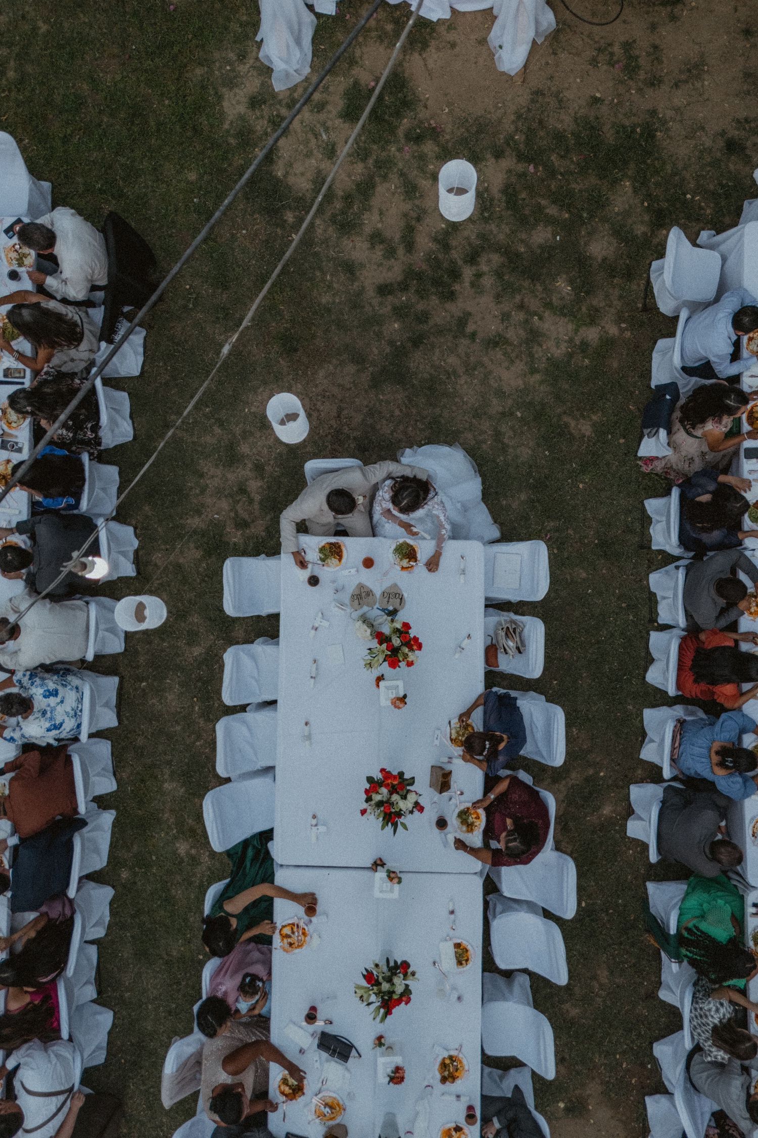 Birds eye view of outdoor wedding dinner setup with white tables and chairs.