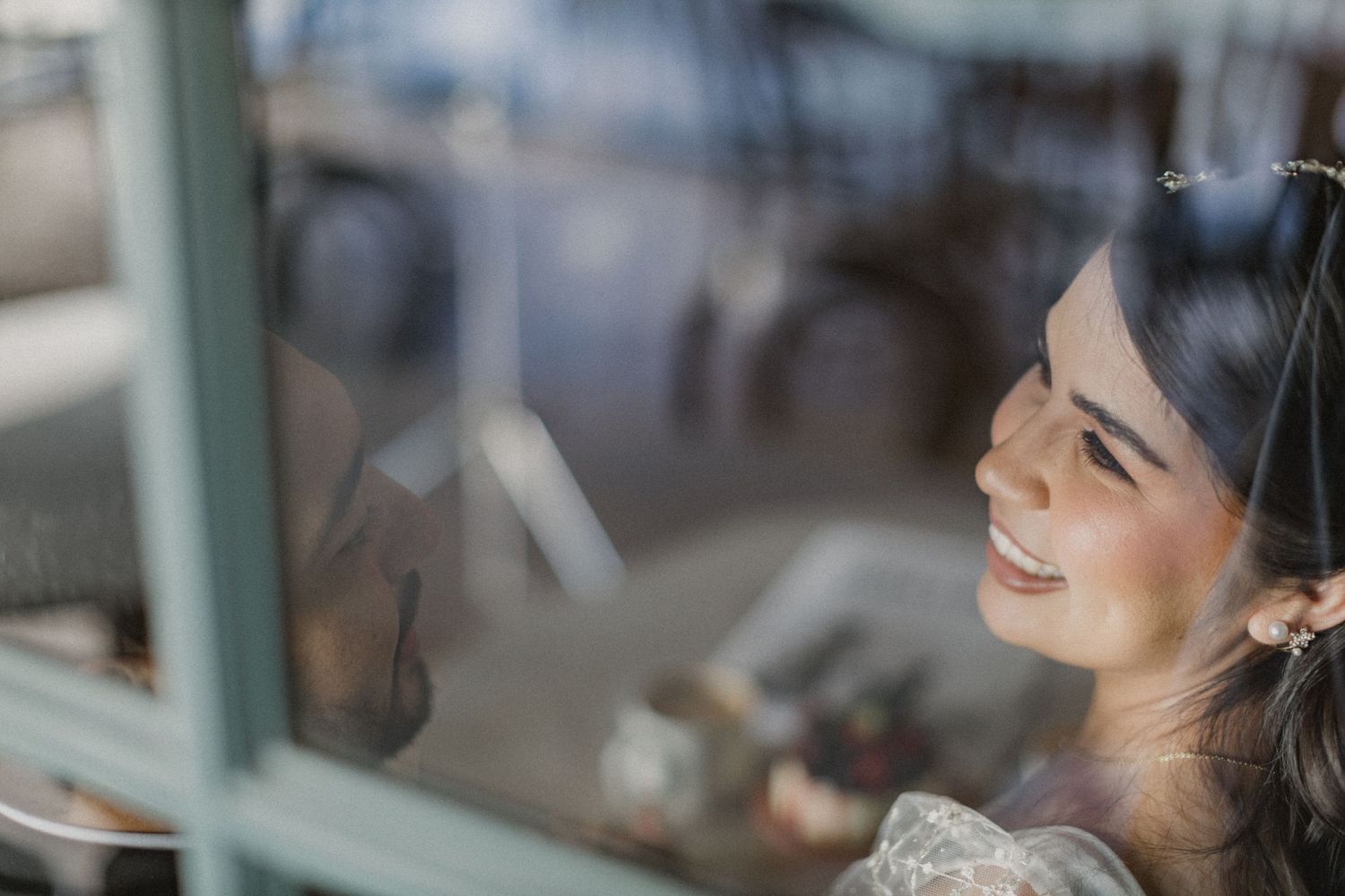 A smiling reflection appears in window glass with soft lighting.