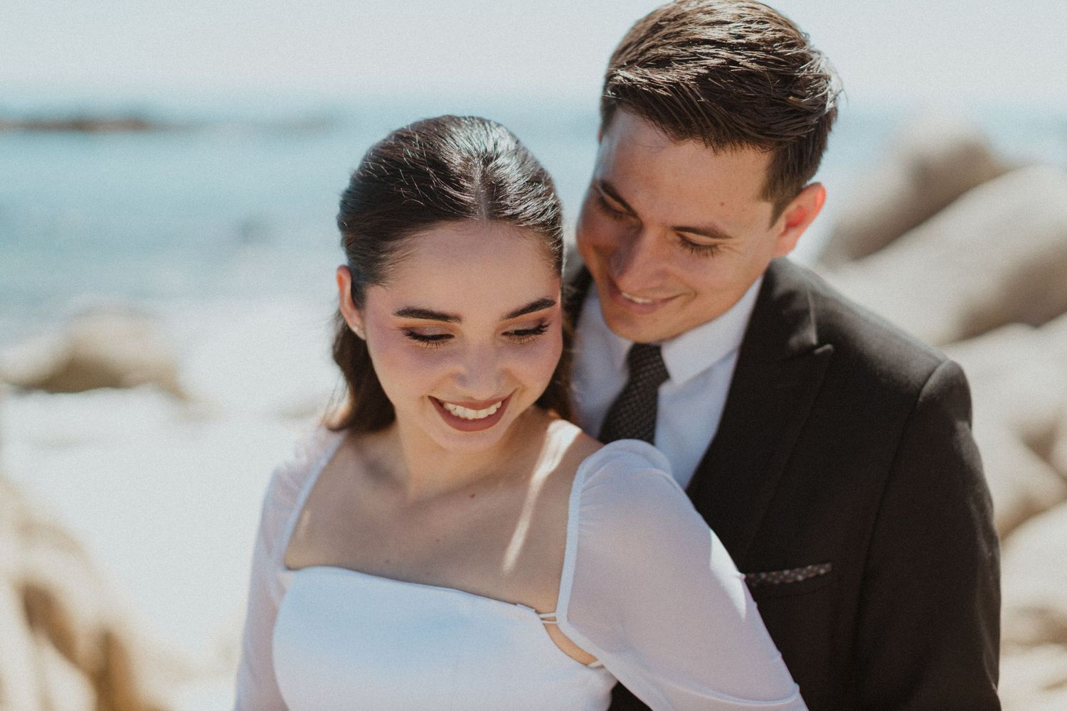 Seaside wedding portrait with rocky coastal background.