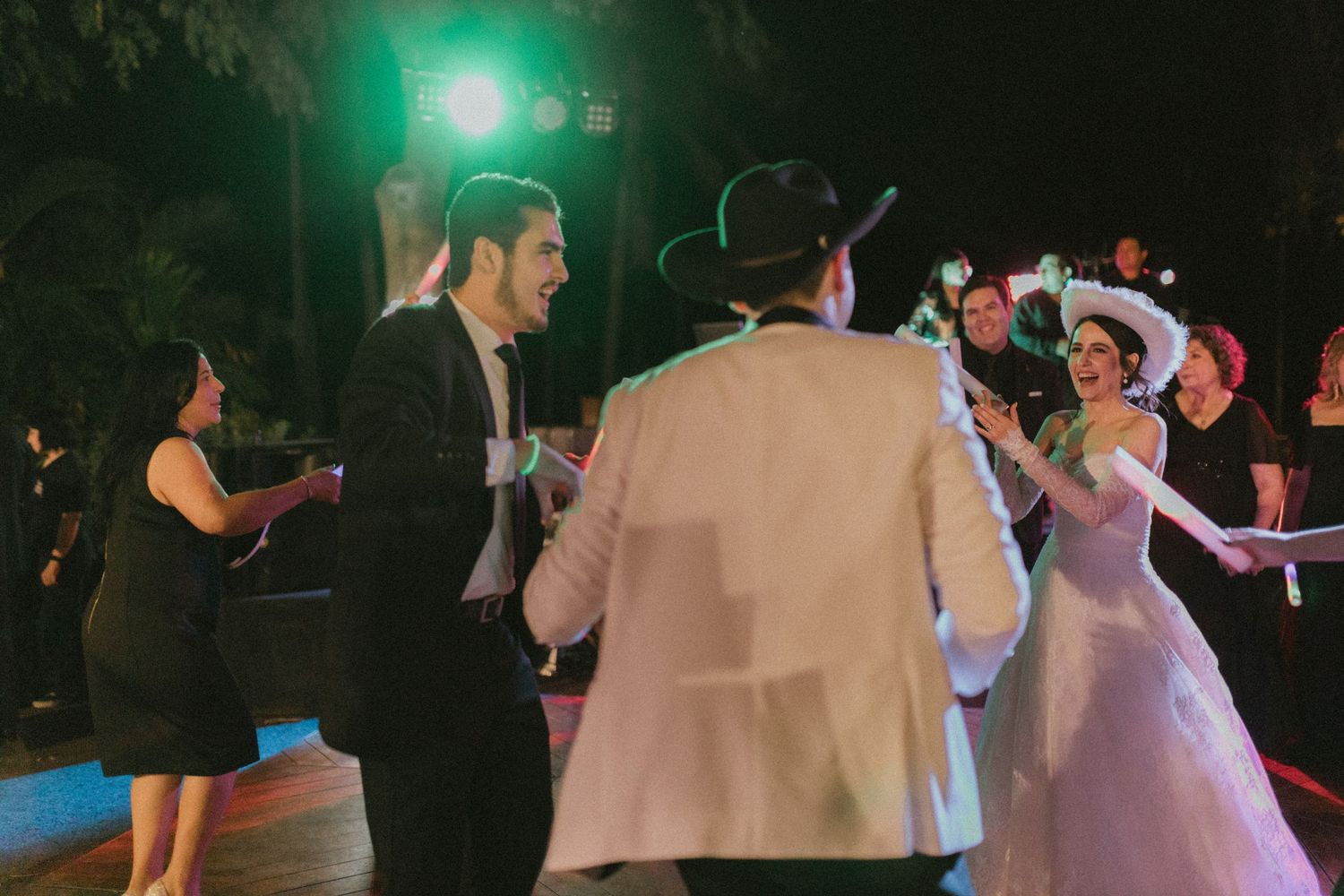 Wedding guests dancing at night under colored lights during the reception.