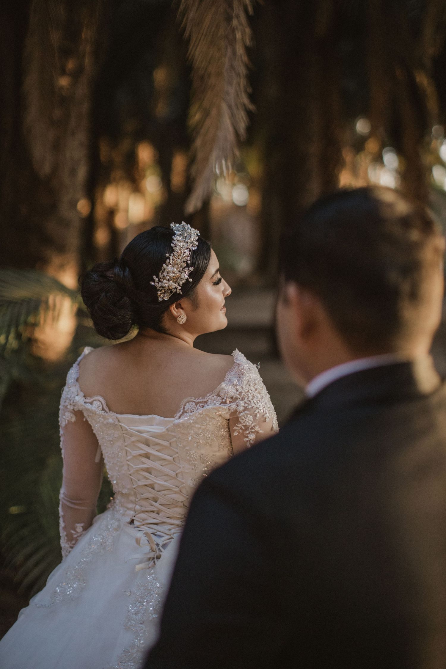 Wedding dress details showing intricate lace corset back and crystal hair accessory.