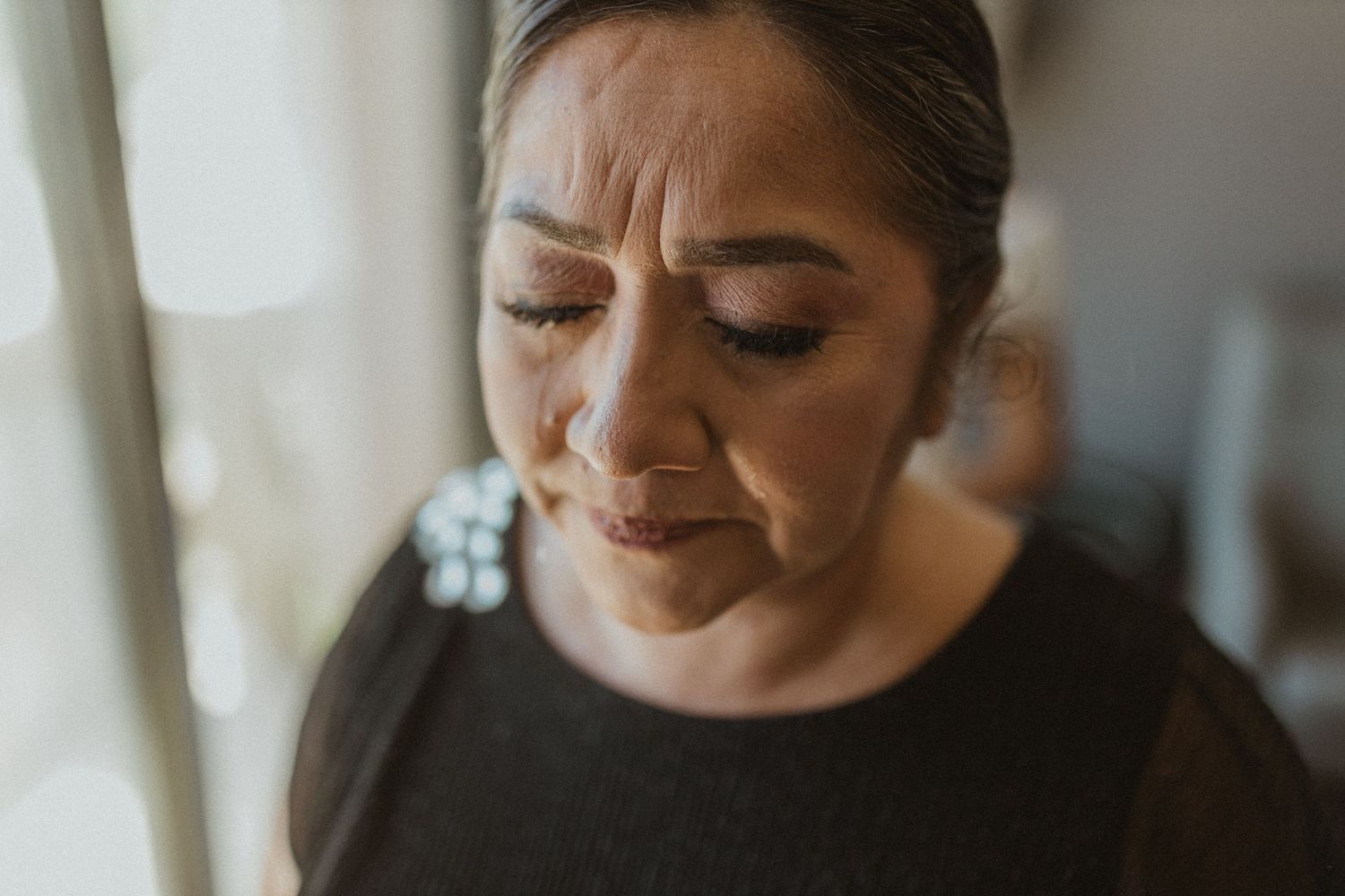 Emotional wedding day preparation moments captured in black and white tones.