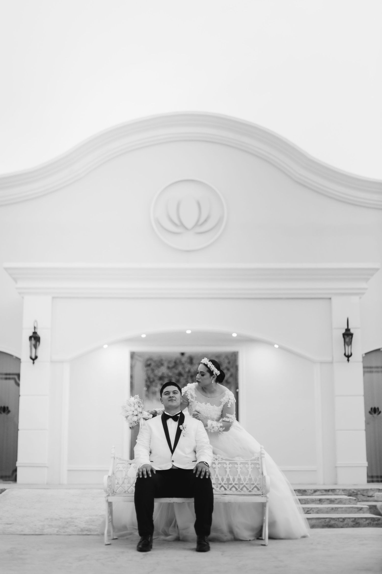 Elegant black and white wedding portrait in a classic white architectural setting.