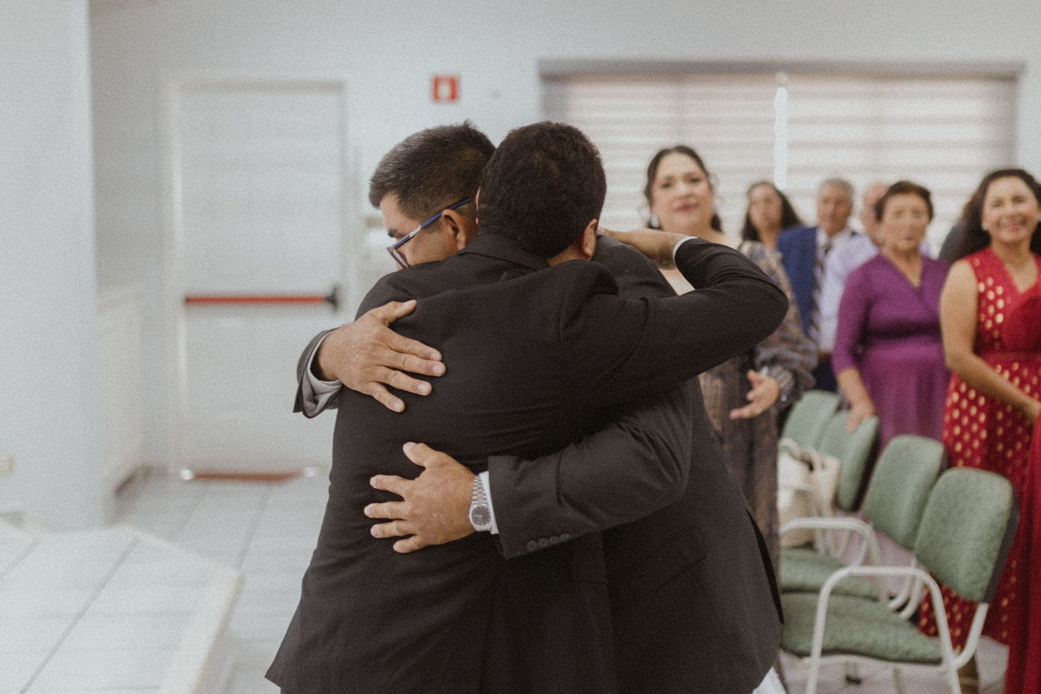 Emotional wedding ceremony moments with family embracing in a bright indoor setting.