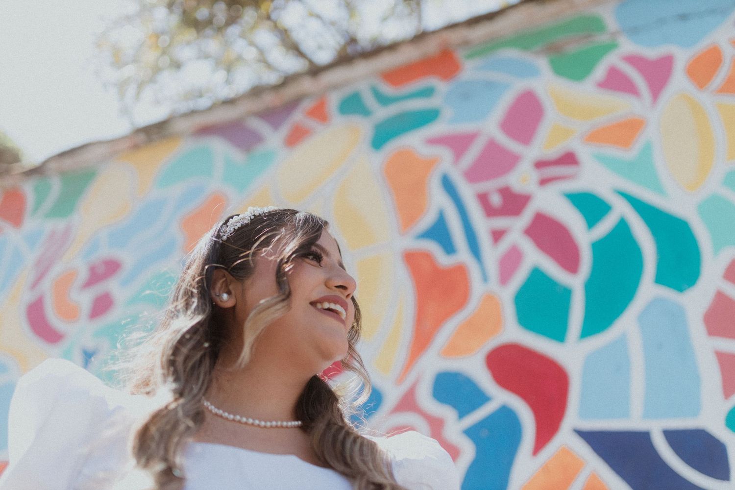 Bright colorful mosaic mural design featuring organic shapes on white wall.