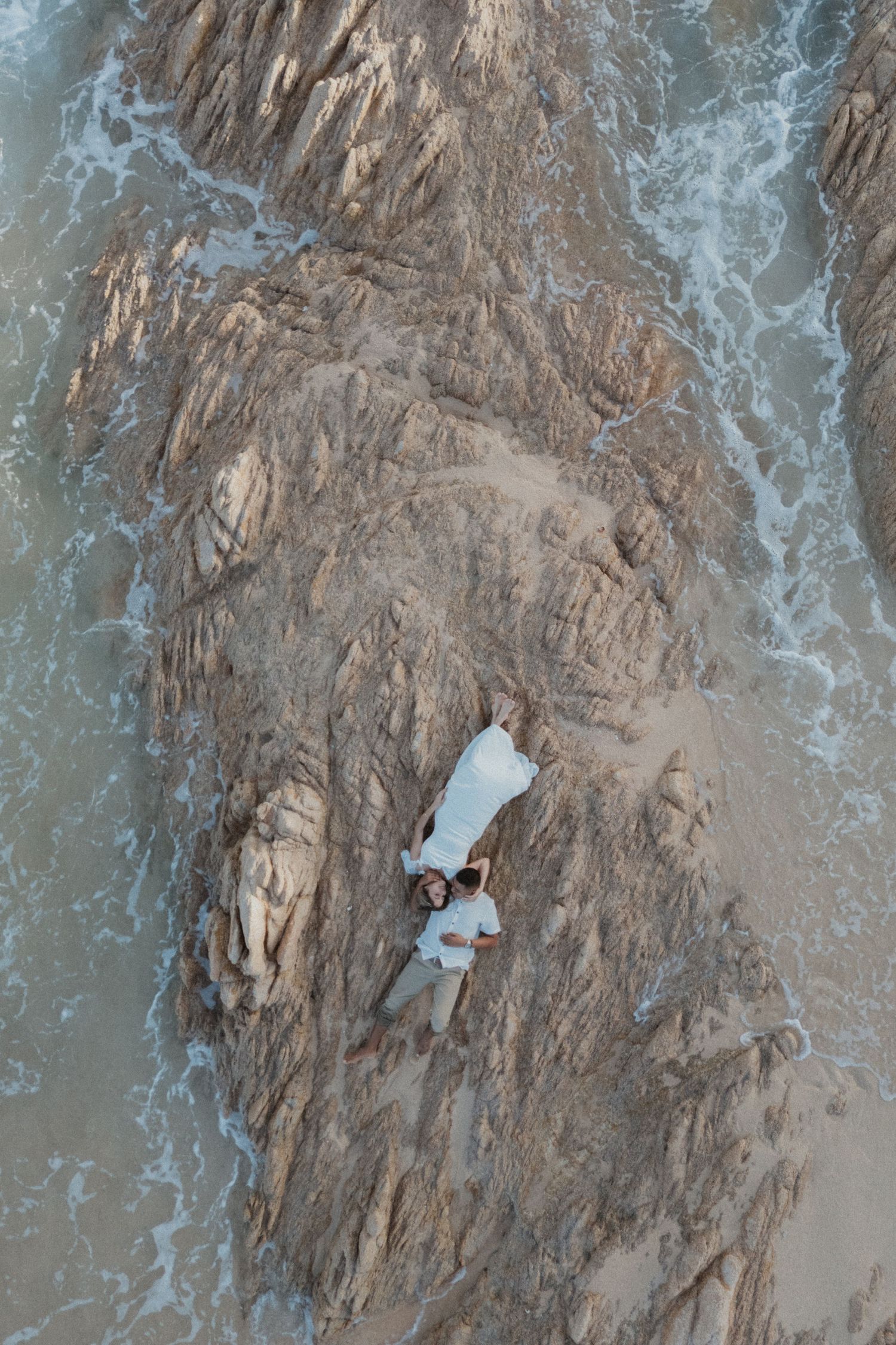Aerial view of rocky coastline with waves crashing against cliffs and sandy beaches.