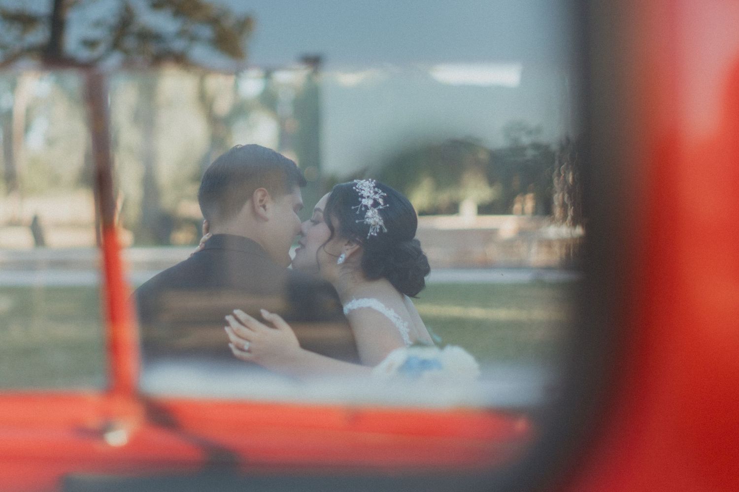Romantic couple's embrace captured through vintage car window reflection.