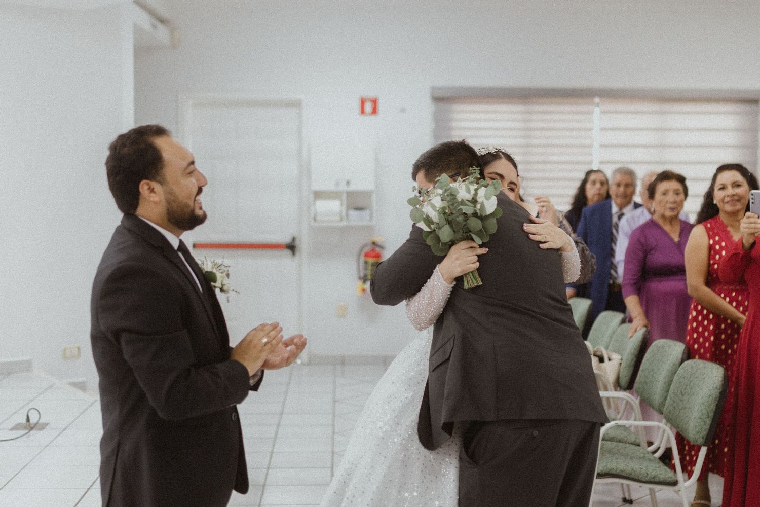 Wedding ceremony in a bright indoor venue with guests looking on.