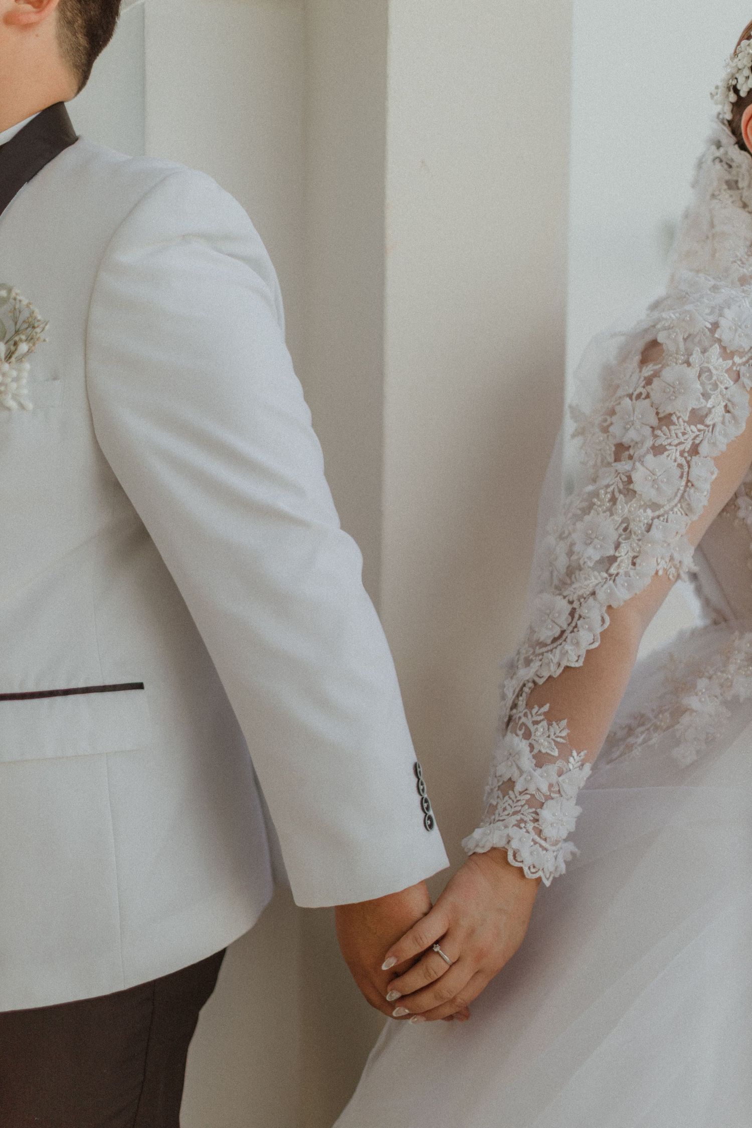 Wedding couple's arms showing intricate lace sleeve details and formal attire.