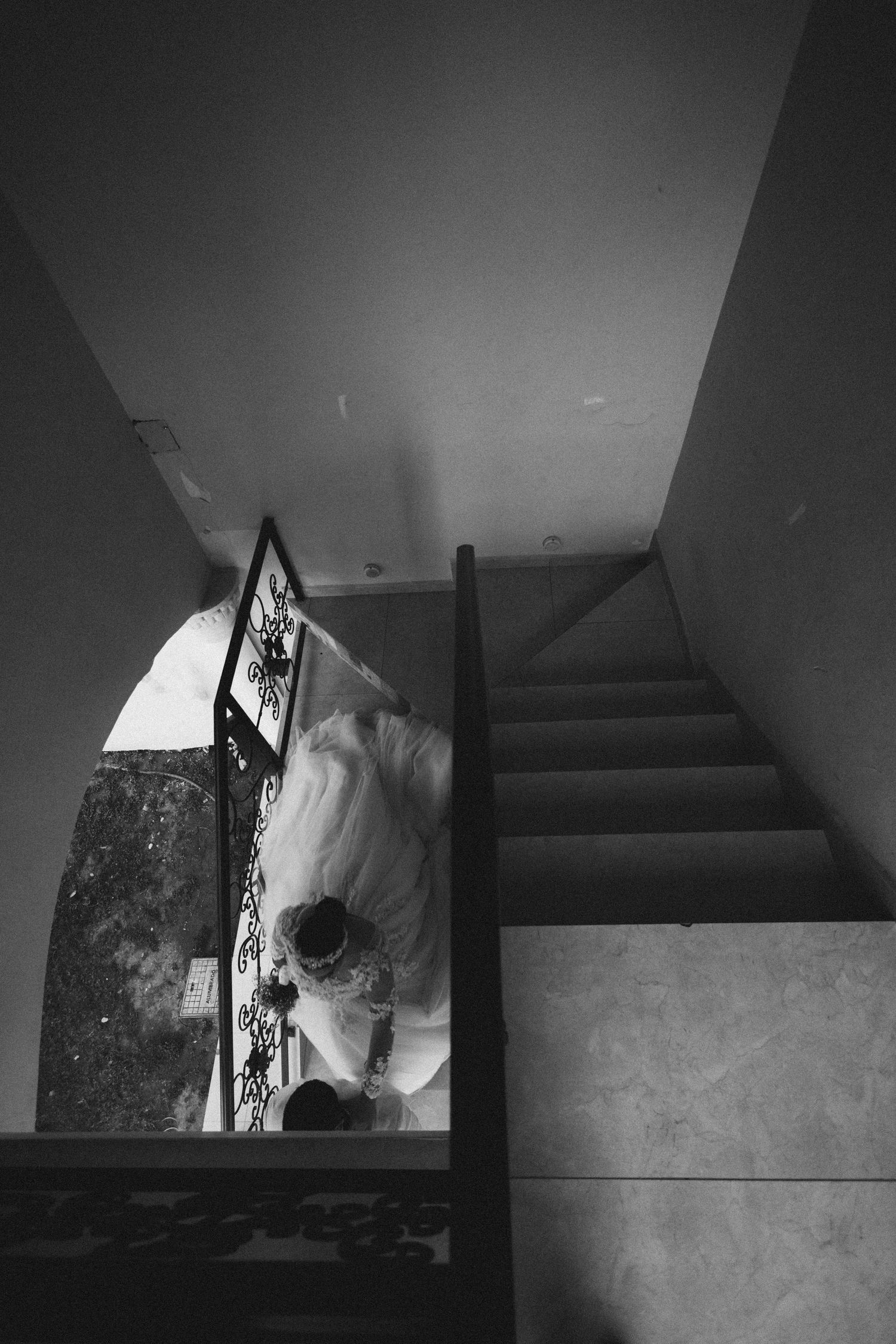 Black and white view looking down a staircase with a dress visible in the corner.
