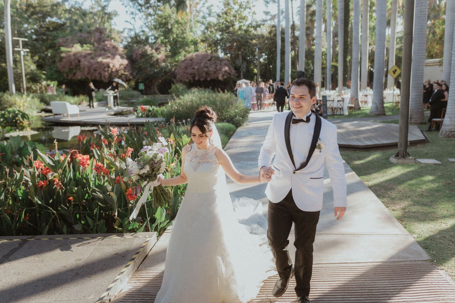 Wedding celebration in a tropical garden path lined with palm trees.