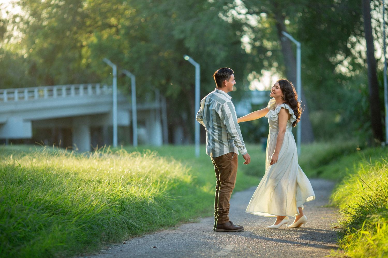 A couple in casual attire sharing a romantic moment on a path during golden hour.