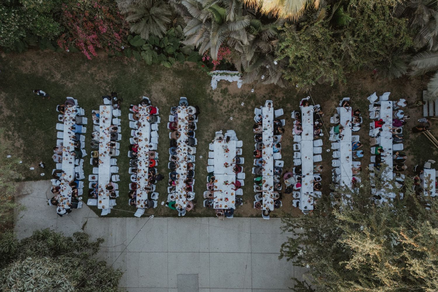 Aerial view of long banquet tables arranged outdoors for a wedding reception.