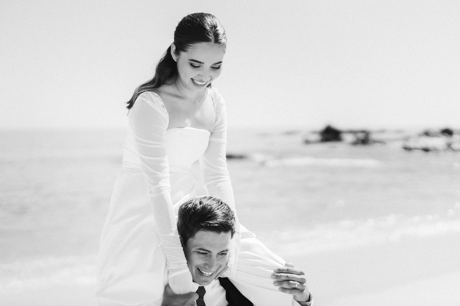 A joyful wedding moment captured in black and white on a beach.