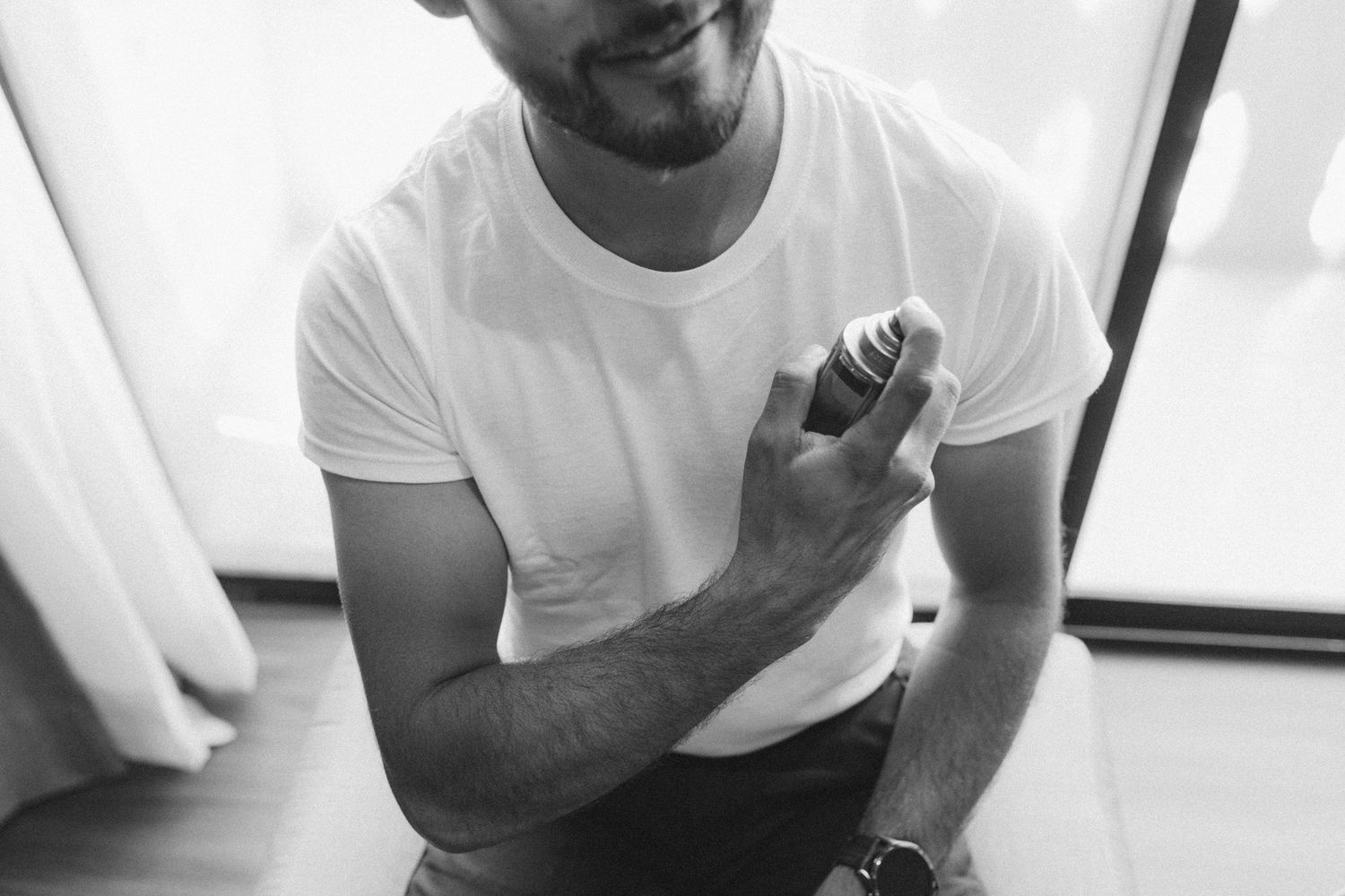 Person in white t-shirt shown from shoulders down sitting casually.