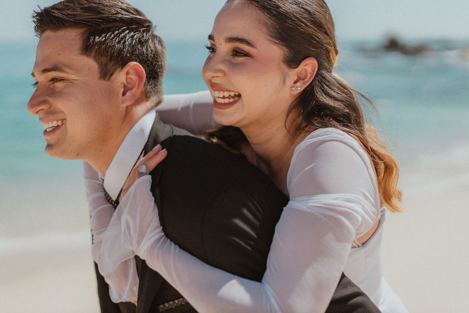 A joyful embrace captured on a beautiful beach with turquoise waters.