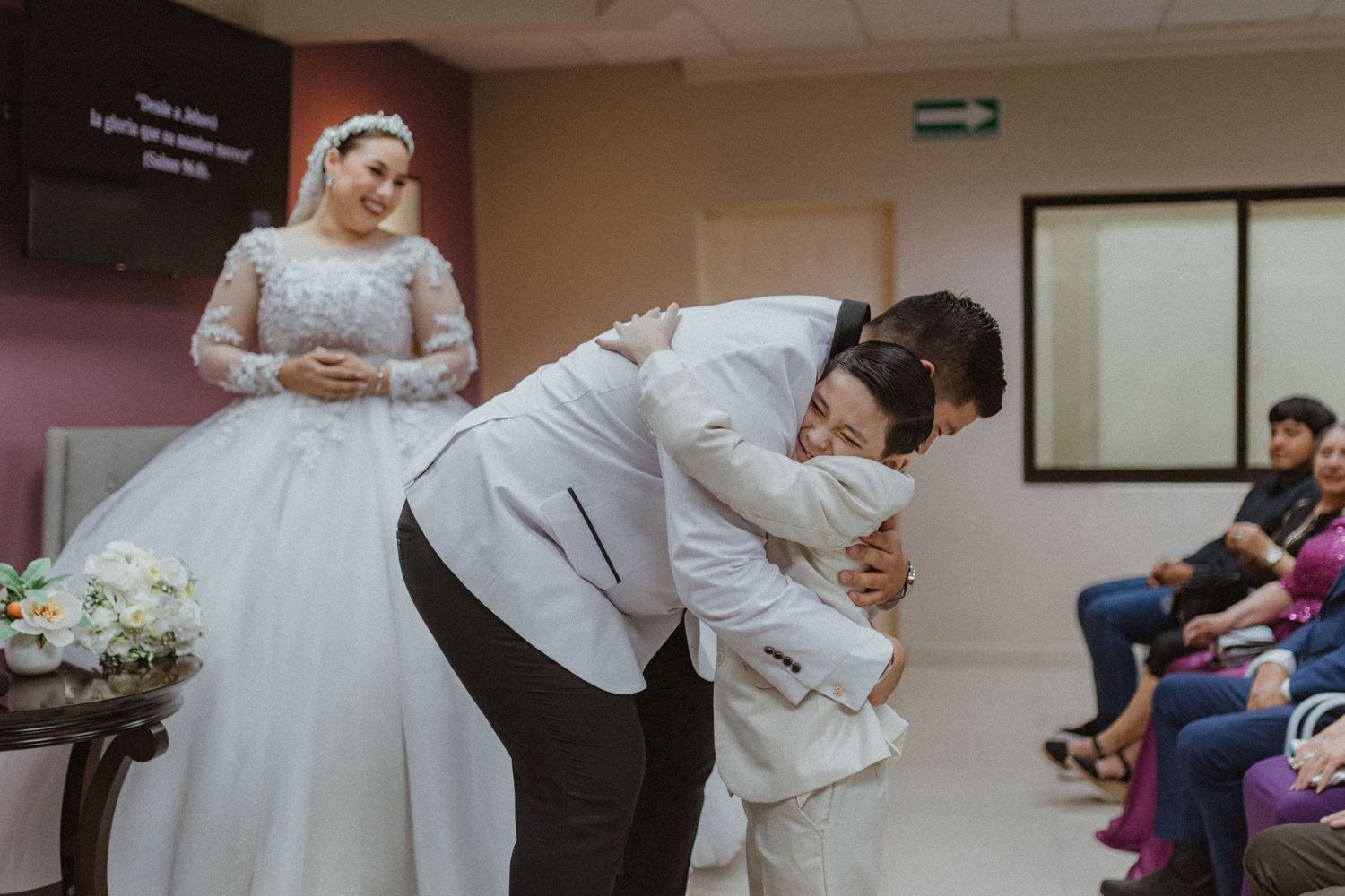 Wedding couple dances and celebrates in indoor venue with guests watching.