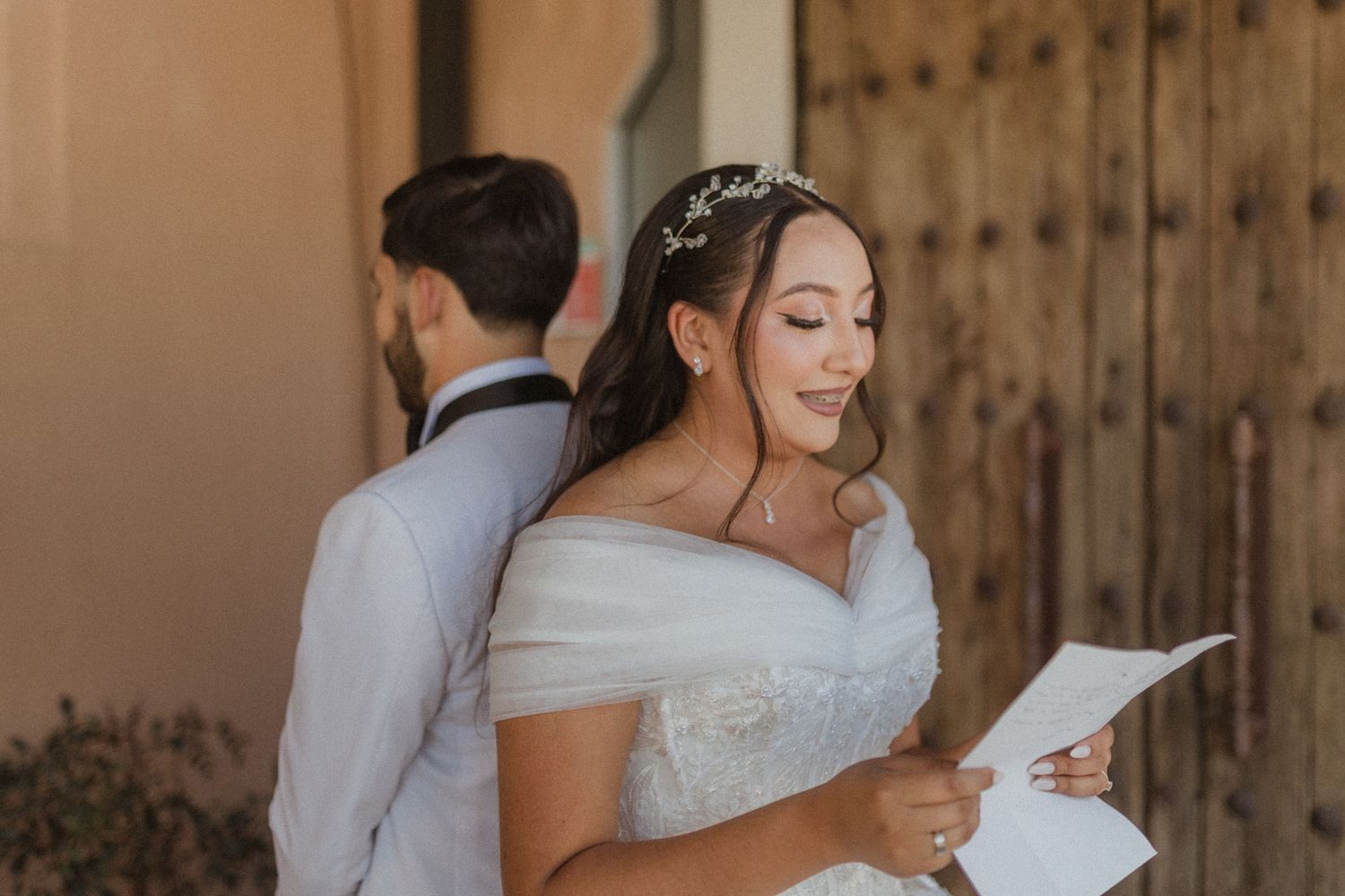 A joyful wedding moment as the couple reads letters separately while standing back to back.