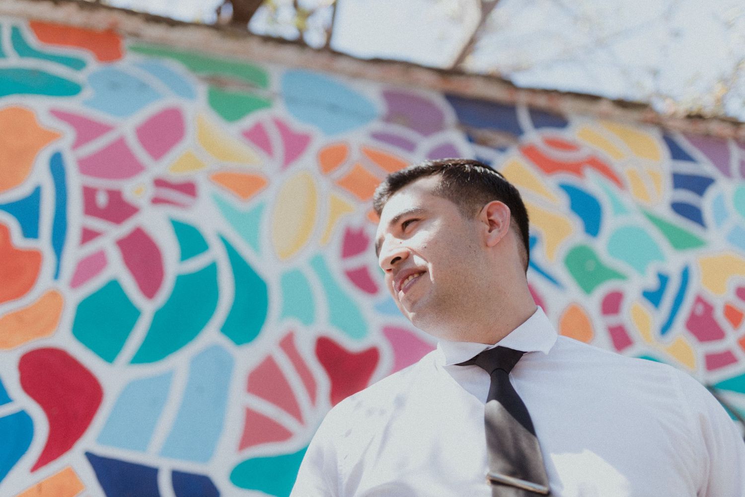Couple sharing a romantic moment against colorful mosaic wall background.