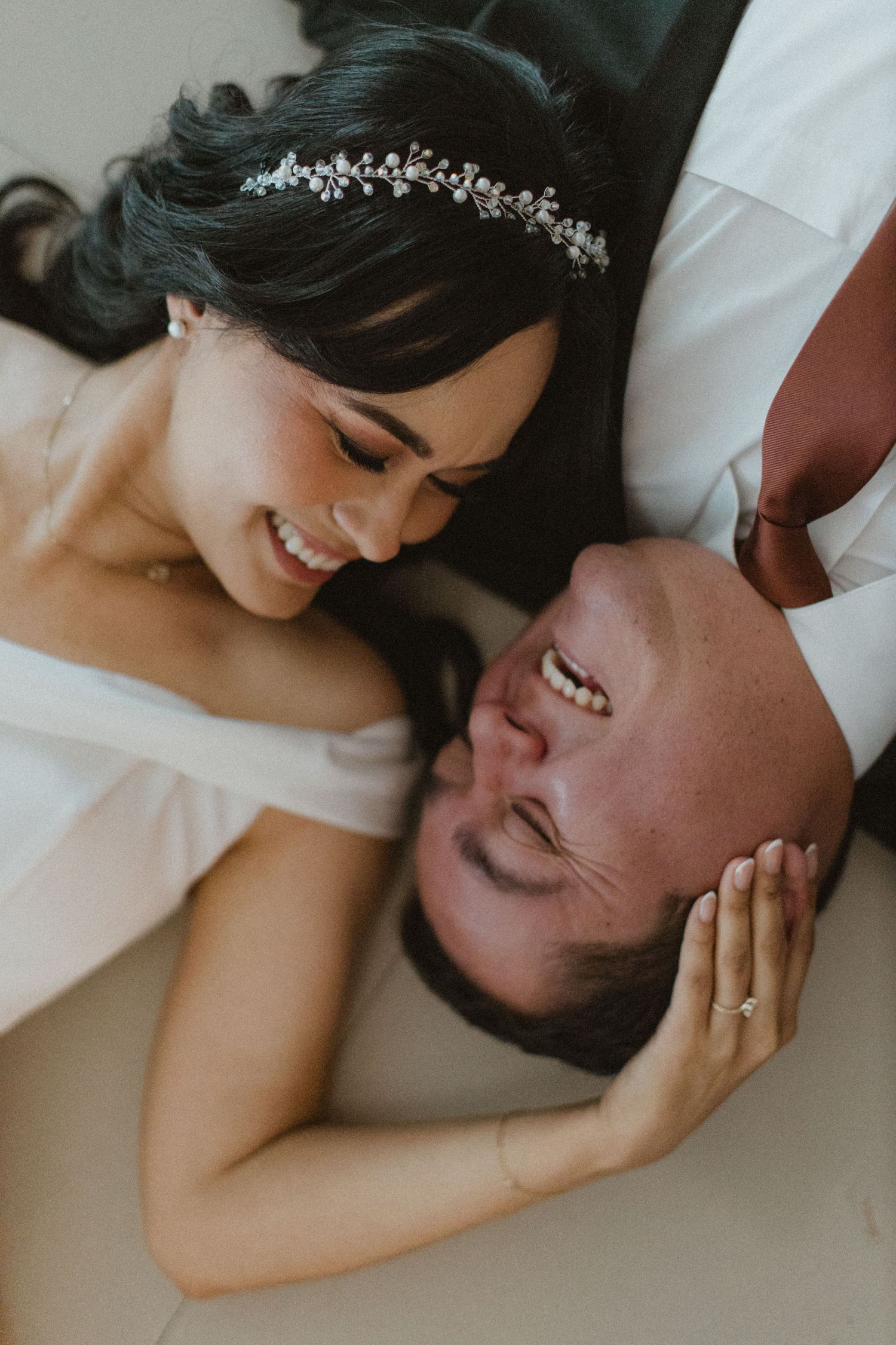 Intimate moment between couple lying down with delicate lace details and jewelry.