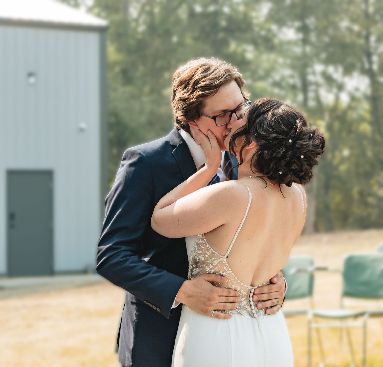 Bride and groom sharing their first kiss as a married couple at outdoor wedding ceremony.