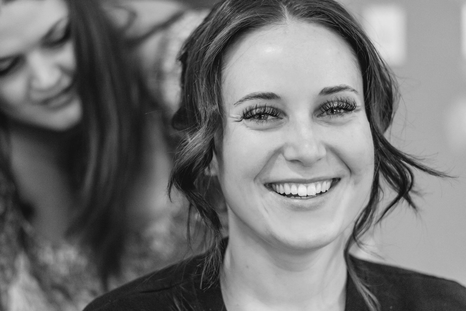 Black and white portrait of a smiling bride with updo hairstyle getting ready on her wedding day.