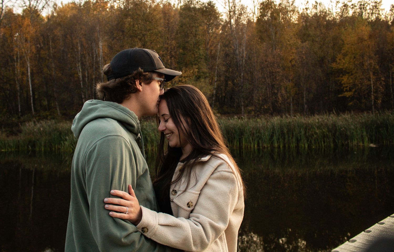 Young couple sharing an intimate moment together on a lakeside dock in fall.