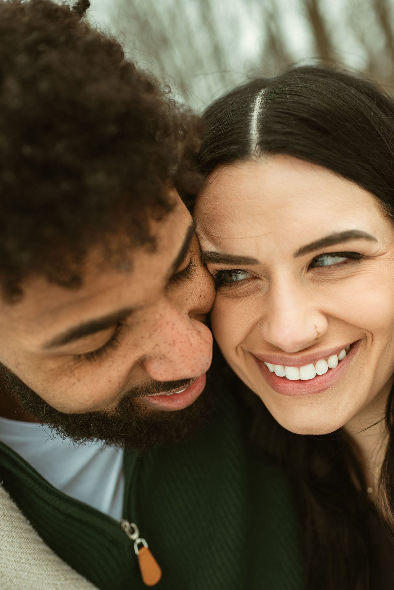 Close-up of a smiling couple sharing an intimate moment together in a warm, candid photoshoot.