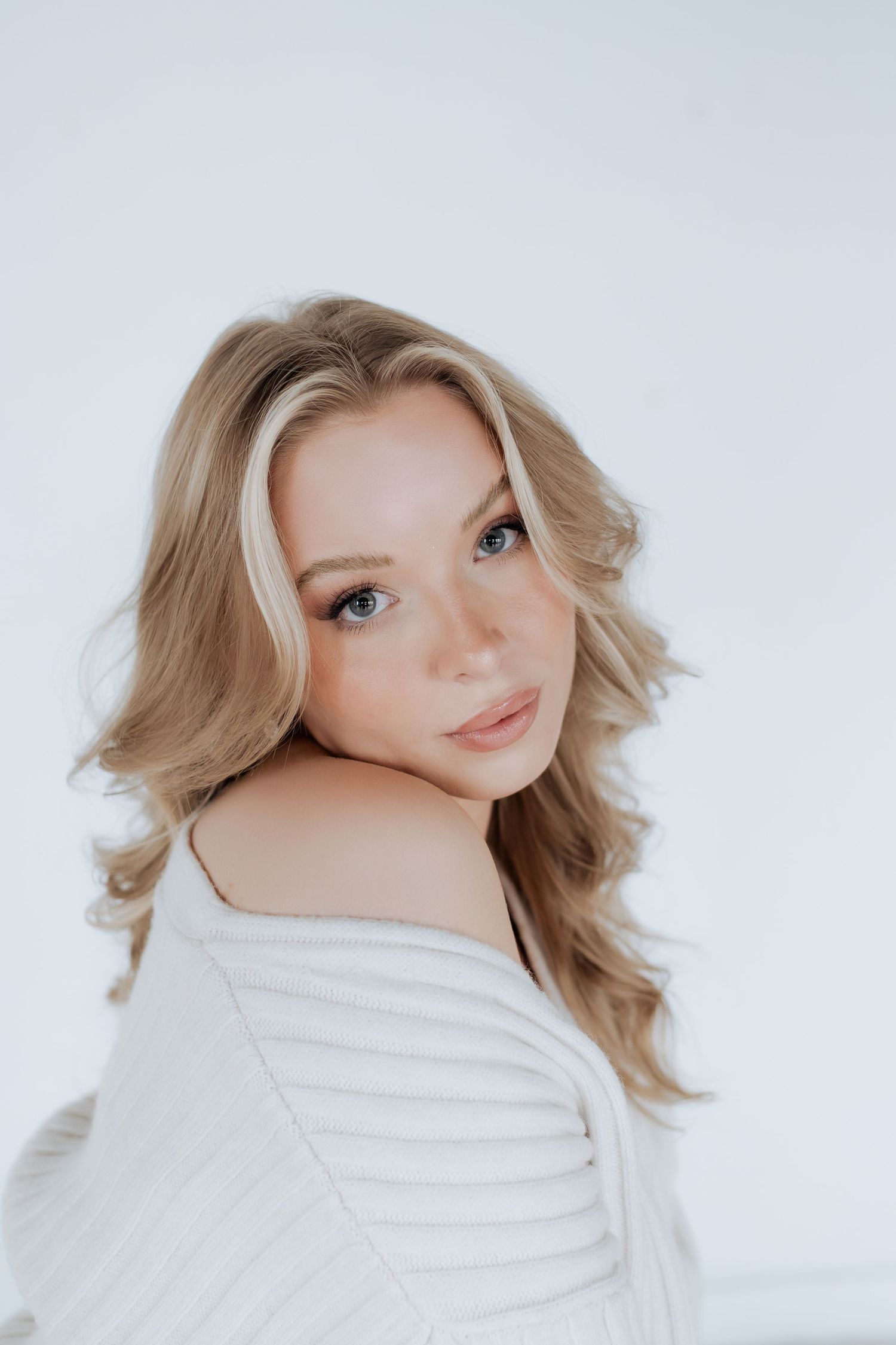 A series of three portrait photos showing a person with blonde hair wearing a white sweater against a light background.
