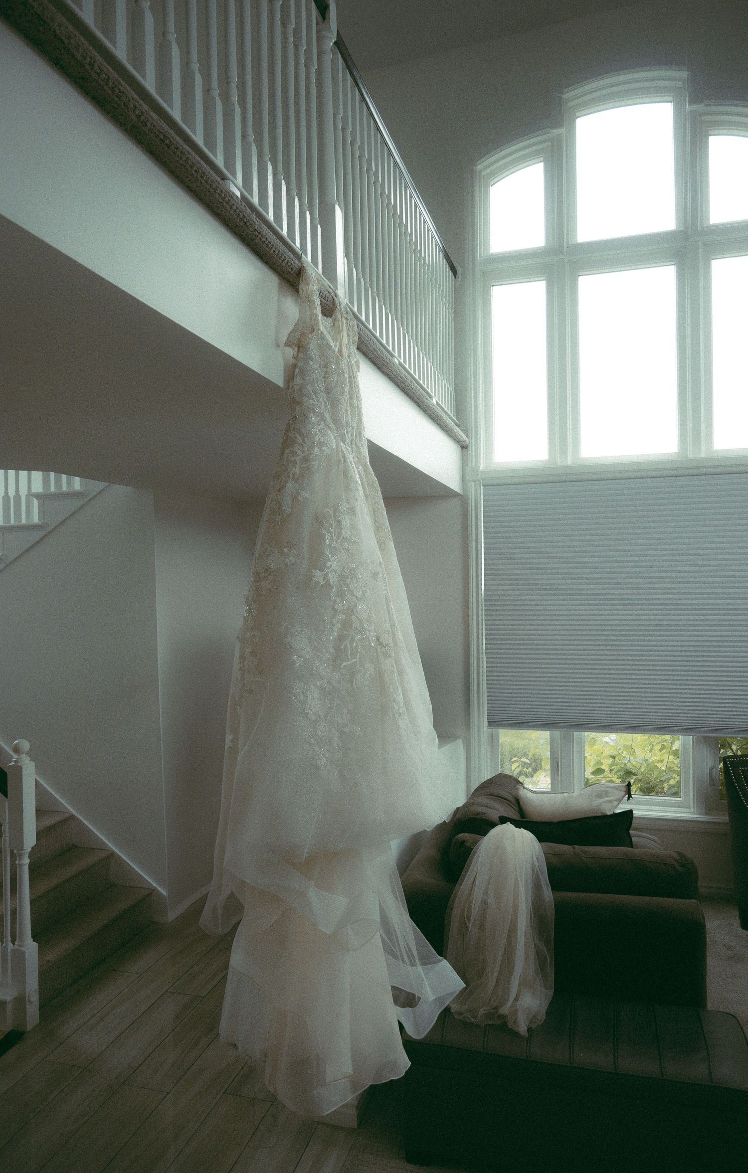 White wedding gowns hanging in a bright room with natural light streaming through windows.