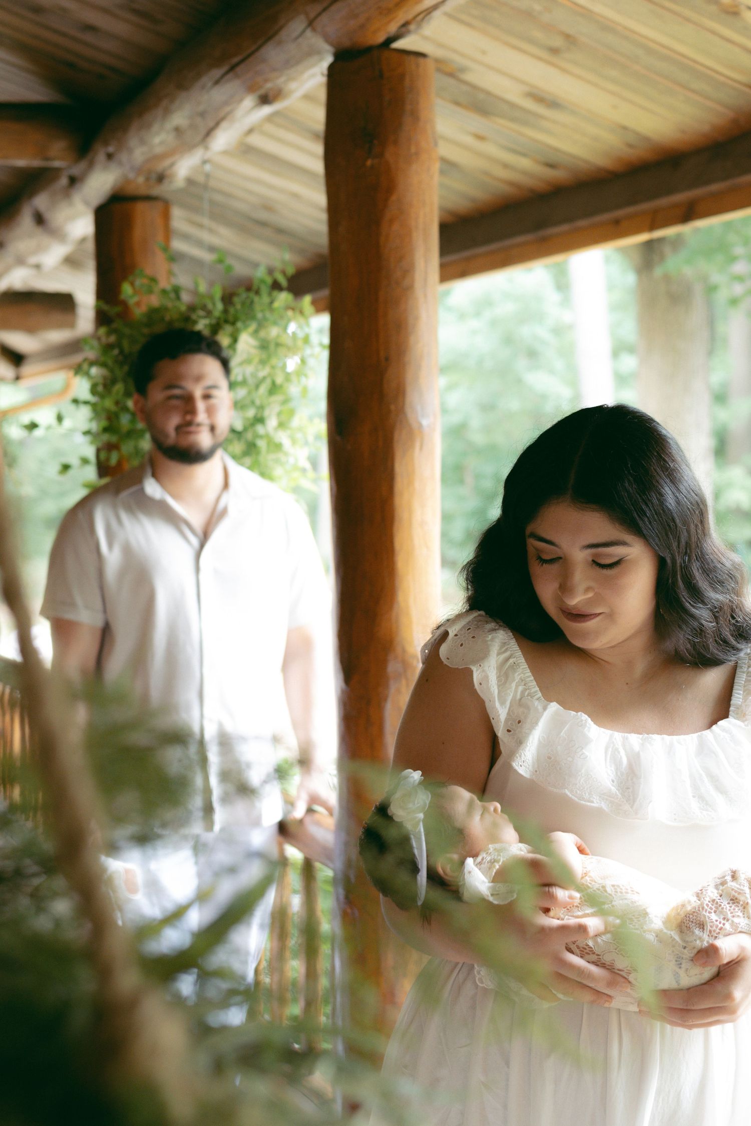 A romantic scene captured in soft natural light under a rustic wooden porch with lush greenery in the foreground.