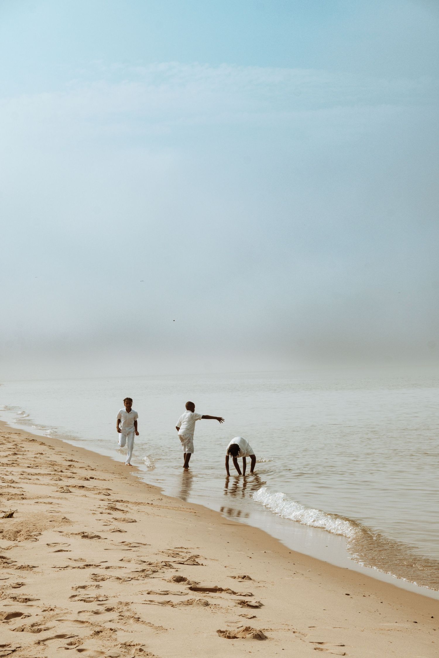 People playing and enjoying leisure time at a misty beach.
