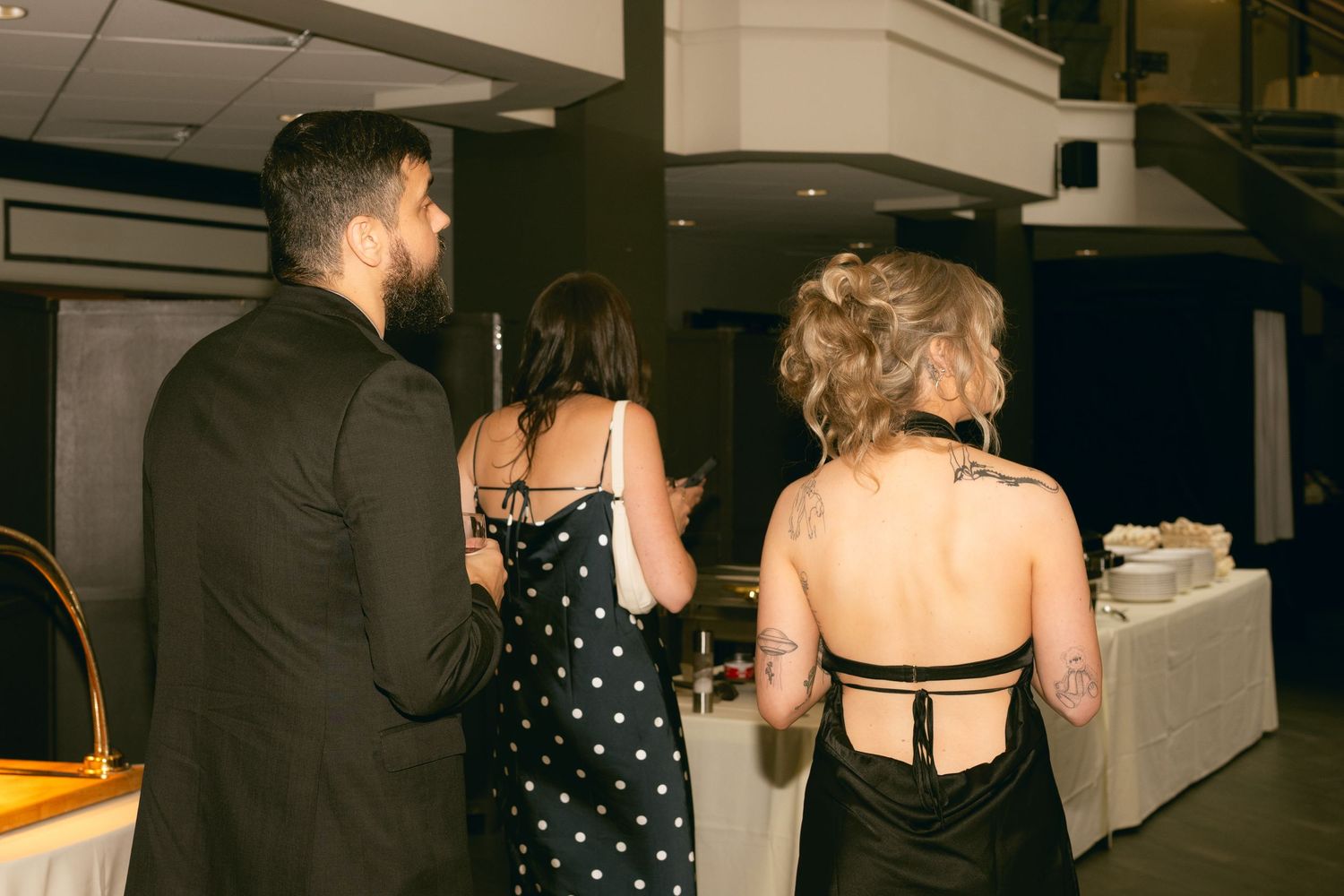 People dancing and socializing at a dimly lit party venue with dark interior decor.