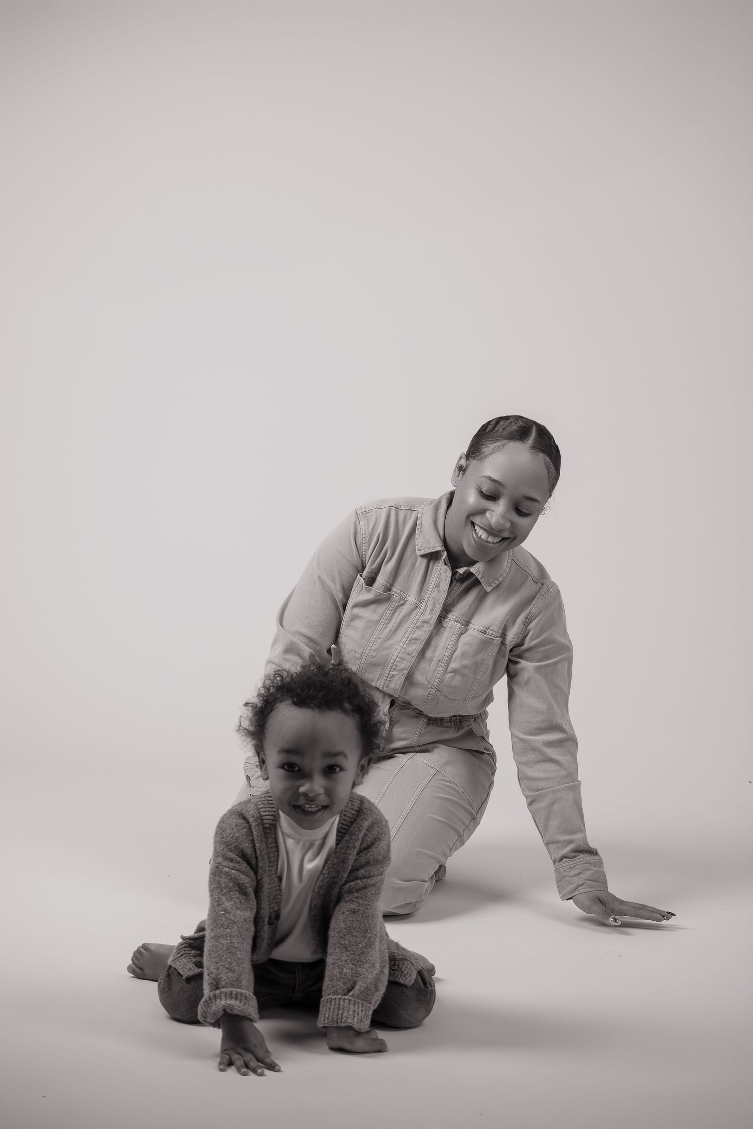 Black and white studio portrait of parent and child in casual attire posing together.