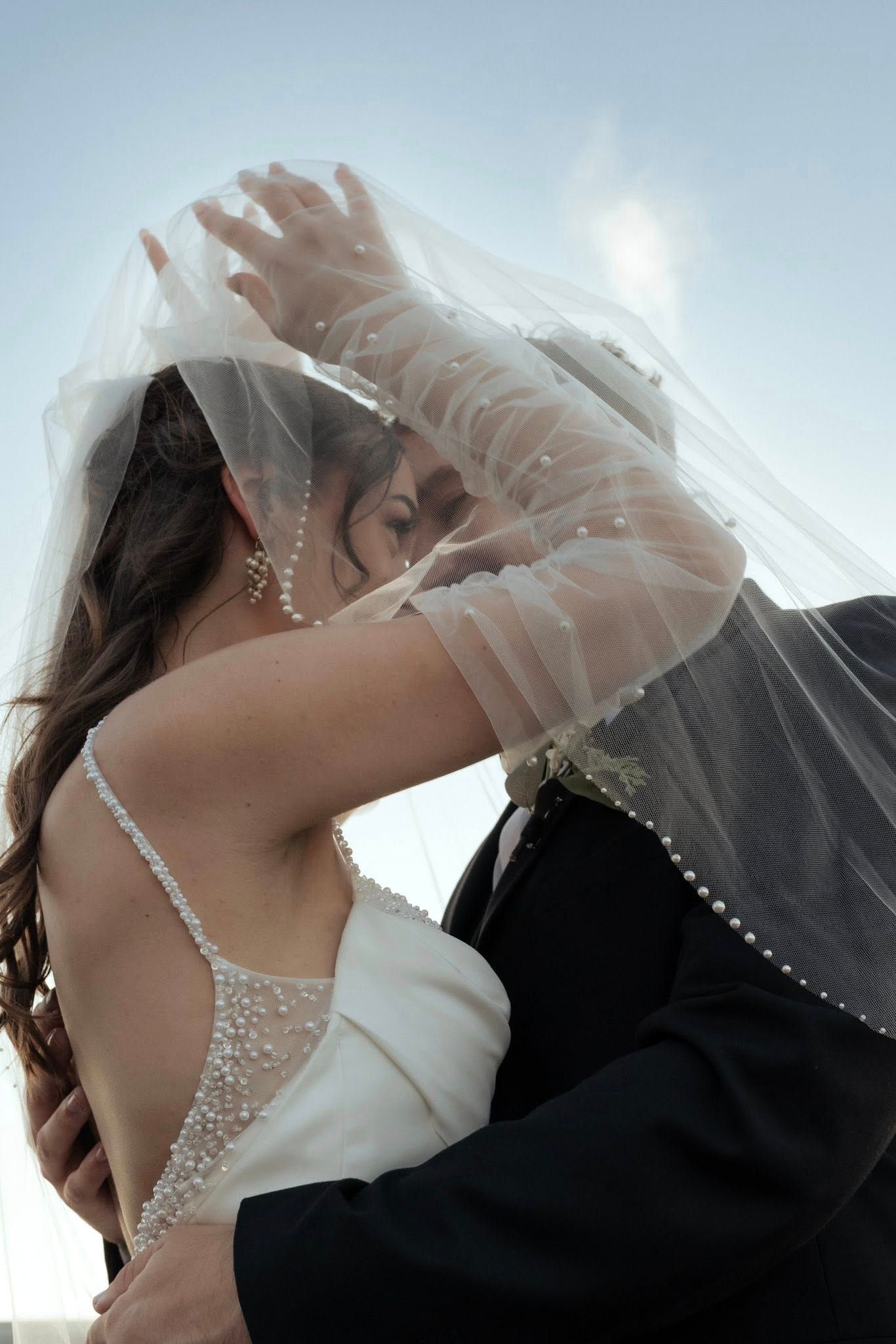 A romantic wedding couple shares an intimate kiss under a delicate white veil in a series of artistic photos.